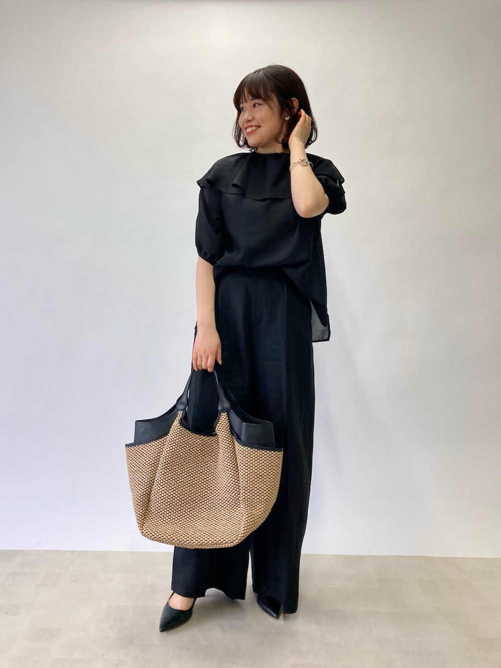 ブラック系のシャツ/ブラウス、ブラック系のかごバッグ、ブラック系のパンプスを着用したレディースの春コーディネートの2枚目の写真