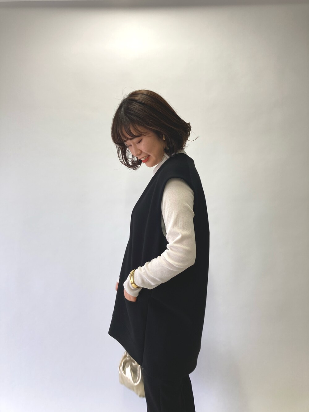 ブラック系のベスト、ホワイト系のTシャツ/カットソー、ゴールド系のショルダーバッグを着用したレディースの春コーディネートの5枚目の写真