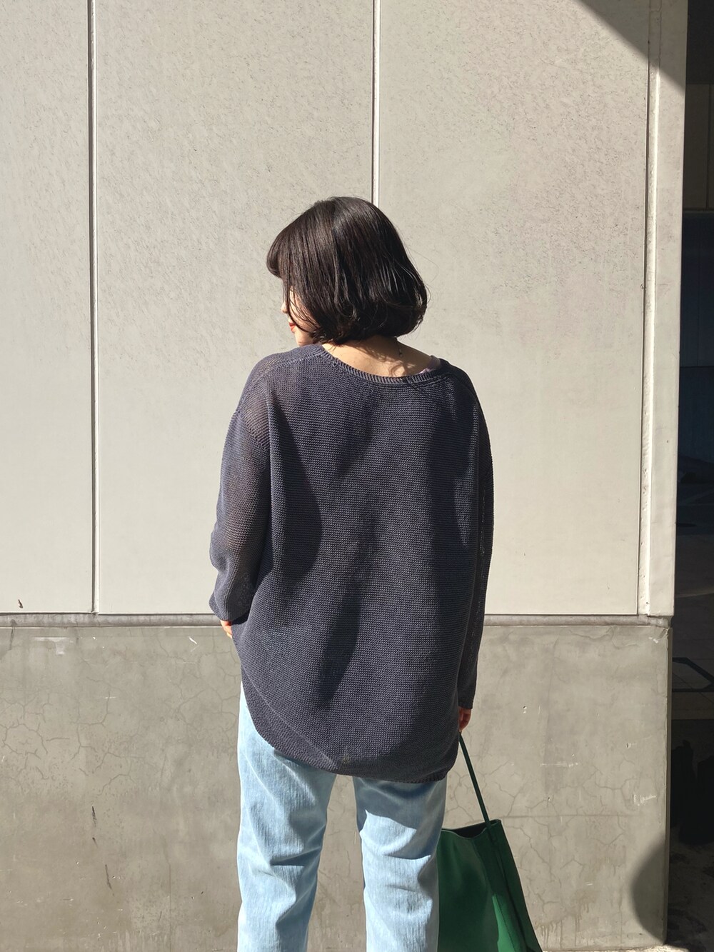 グレー系のニット/セーター、ブルー系のデニムパンツ、グリーン系のトートバッグを着用したレディースの冬コーディネートの3枚目の写真