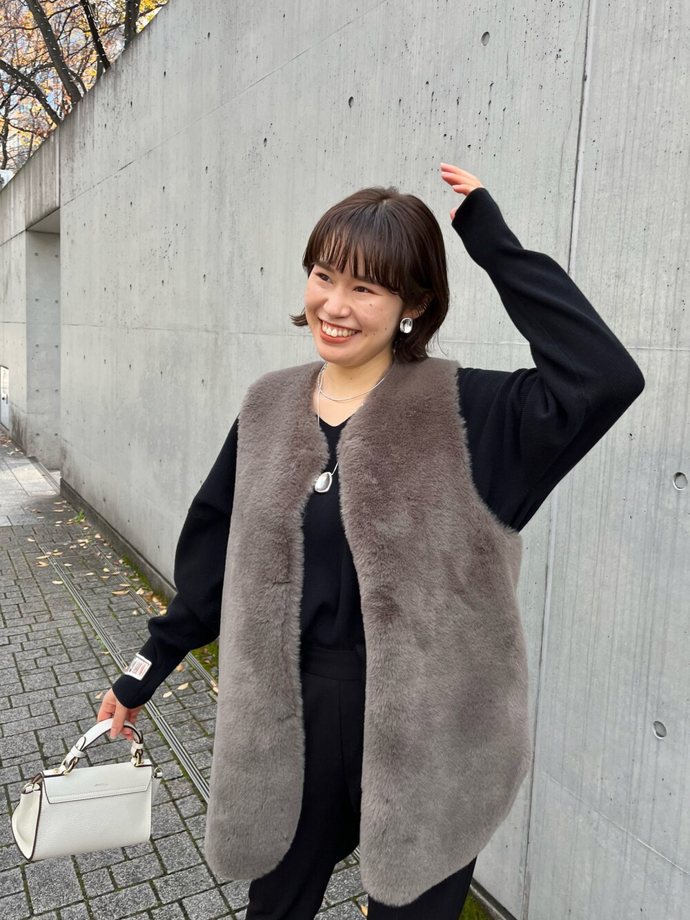 ブラウン系のベスト、ブラック系のその他パンツ、ホワイト系のショルダーバッグを着用したレディースの冬コーディネートの4枚目の写真