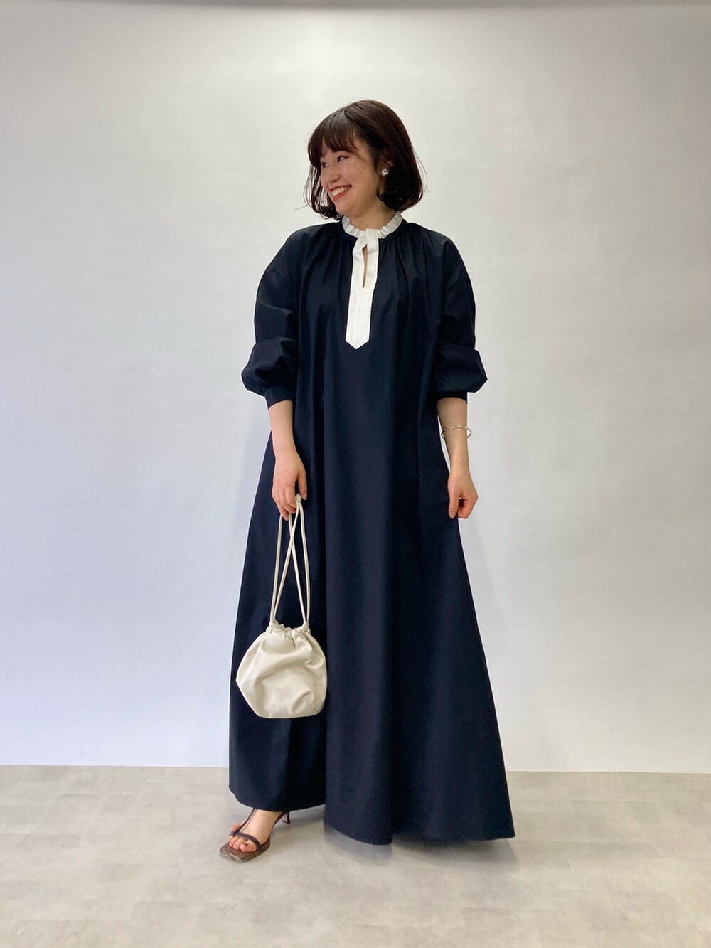 ブラック系のワンピース、ホワイト系のショルダーバッグ、ブラウン系のサンダルを着用したレディースの春コーディネートの2枚目の写真