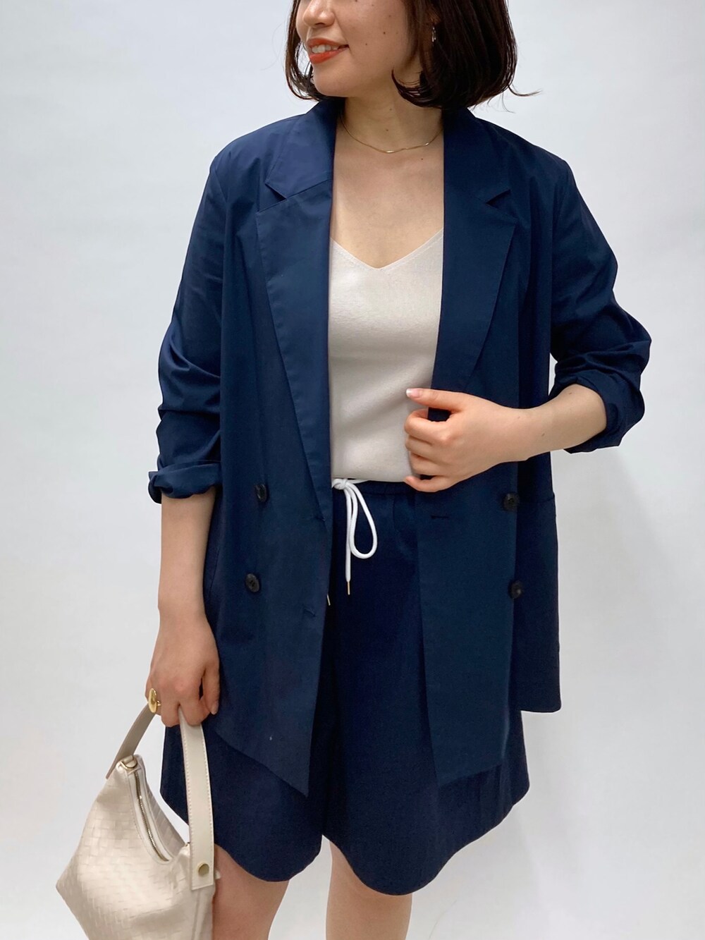 ブルー系のテーラードジャケット、ベージュ系のサンダル、ゴールド系のリングを着用したレディースの春コーディネートの2枚目の写真