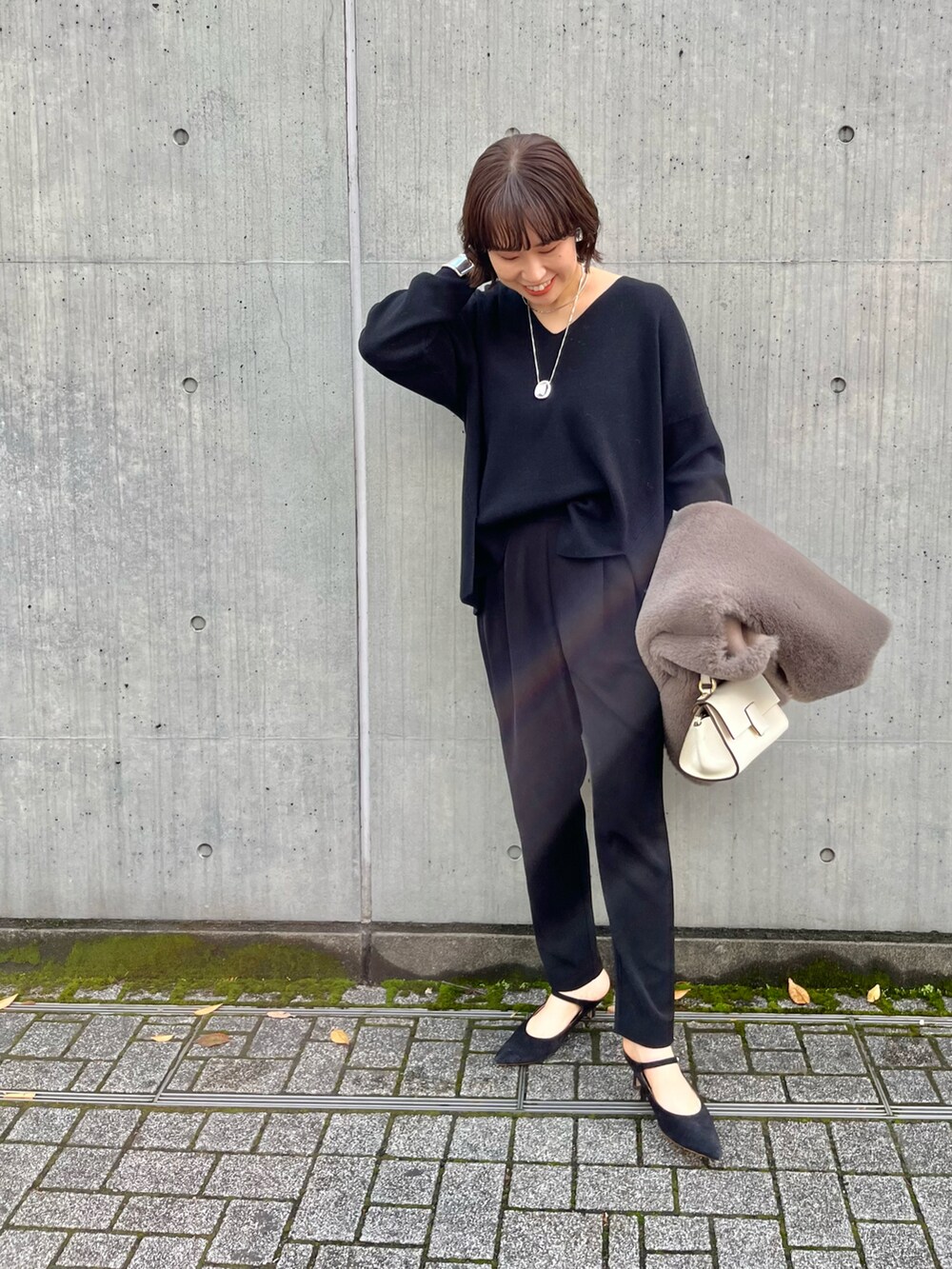 ブラウン系のベスト、ブラック系のその他パンツ、ホワイト系のショルダーバッグを着用したレディースの冬コーディネートの5枚目の写真