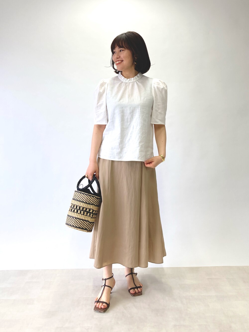 ホワイト系のシャツ/ブラウス、ベージュ系のスカート、ベージュ系のかごバッグを着用したレディースの春コーディネートの3枚目の写真