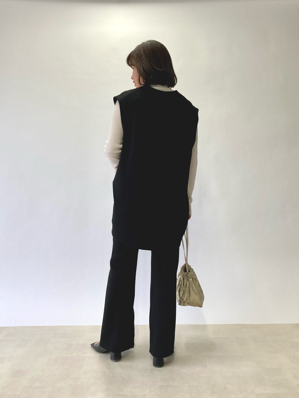 ブラック系のベスト、ホワイト系のTシャツ/カットソー、ゴールド系のショルダーバッグを着用したレディースの春コーディネートの4枚目の写真