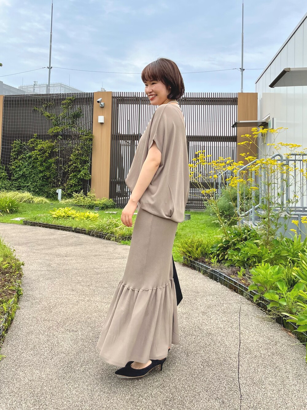 ブラウン系のニット/セーター、ブラウン系のスカート、ブラック系のパンプスを着用したレディースの夏コーディネートの2枚目の写真