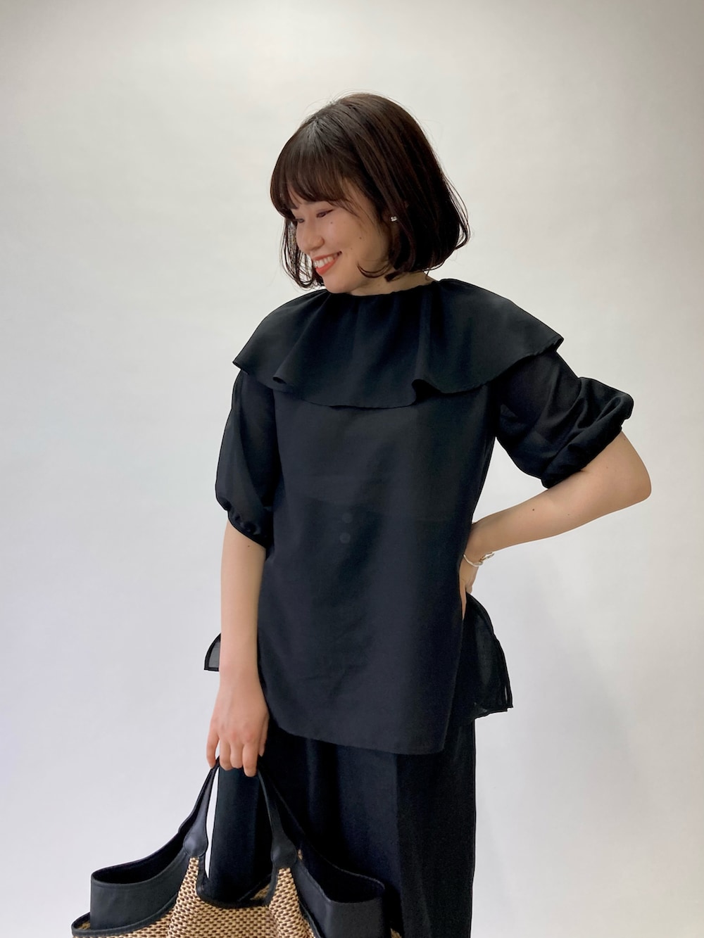 ブラック系のシャツ/ブラウス、ブラック系のかごバッグ、ブラック系のパンプスを着用したレディースの春コーディネートの3枚目の写真