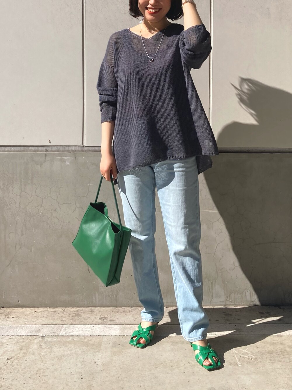 グレー系のニット/セーター、ブルー系のデニムパンツ、グリーン系のトートバッグを着用したレディースの冬コーディネートの4枚目の写真