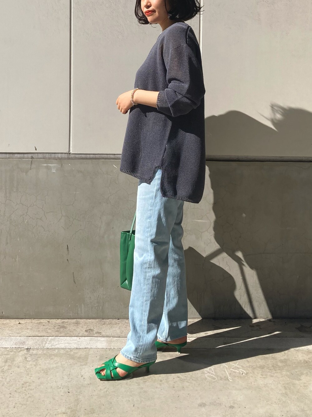 グレー系のニット/セーター、ブルー系のデニムパンツ、グリーン系のトートバッグを着用したレディースの冬コーディネートの2枚目の写真