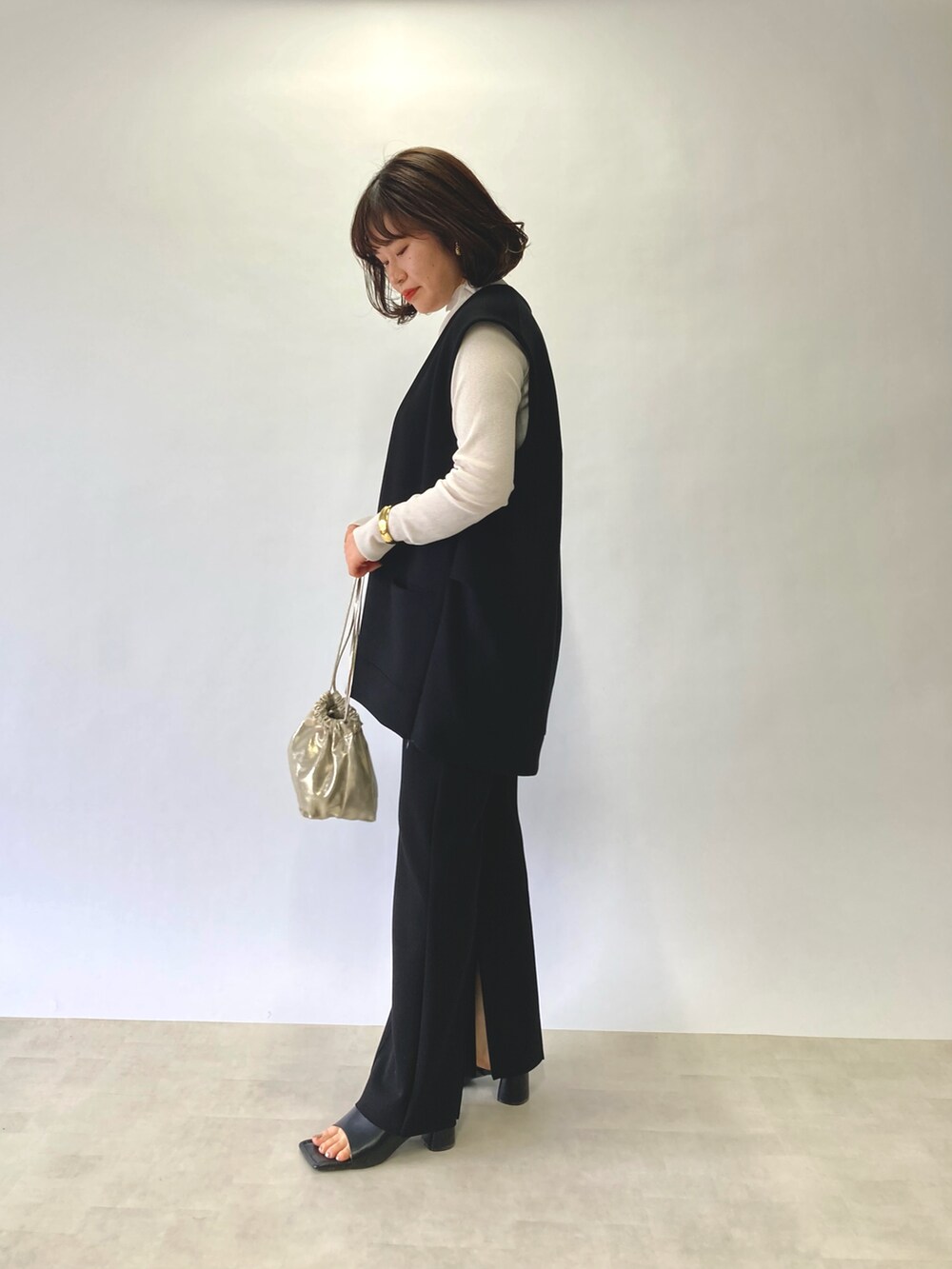 ブラック系のベスト、ホワイト系のTシャツ/カットソー、ゴールド系のショルダーバッグを着用したレディースの春コーディネートの3枚目の写真
