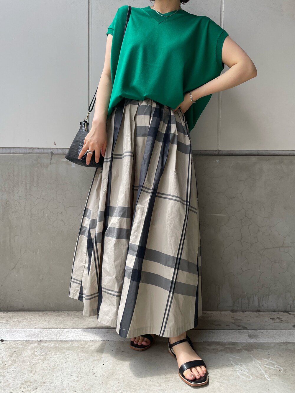 グリーン系のニット/セーター、ホワイト系のスカート、ブラック系のサンダルを着用したレディースの春コーディネートの2枚目の写真