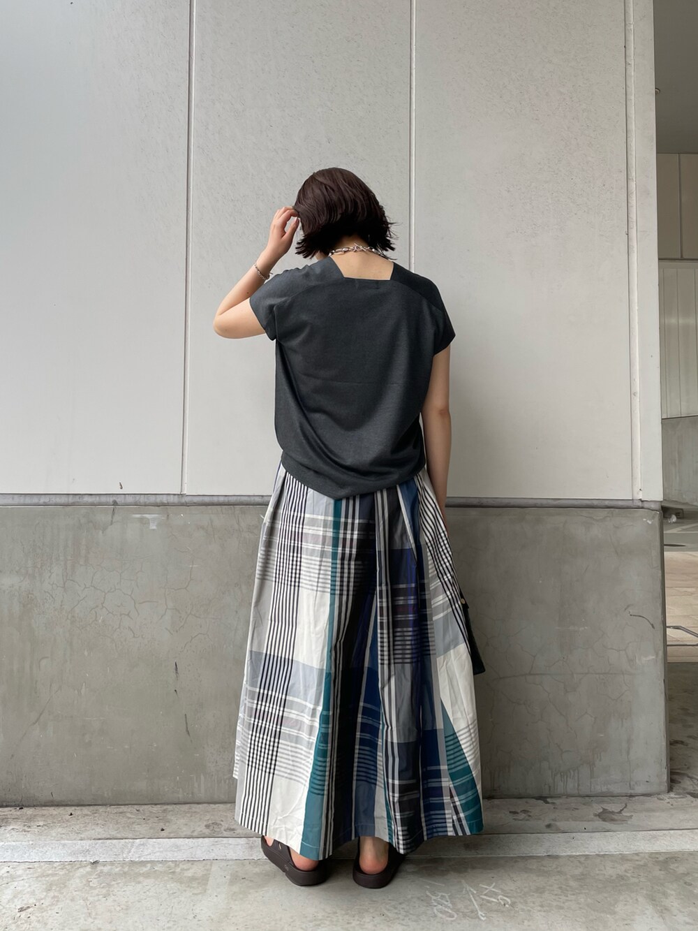 グレー系のTシャツ/カットソー、ブルー系のスカート、ブラウン系のサンダルを着用したレディースの春コーディネートの2枚目の写真