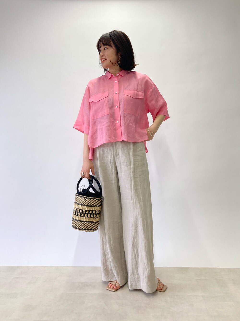 ピンク系のシャツ/ブラウス、ベージュ系のかごバッグ、ベージュ系のサンダルを着用したレディースの春コーディネートの2枚目の写真