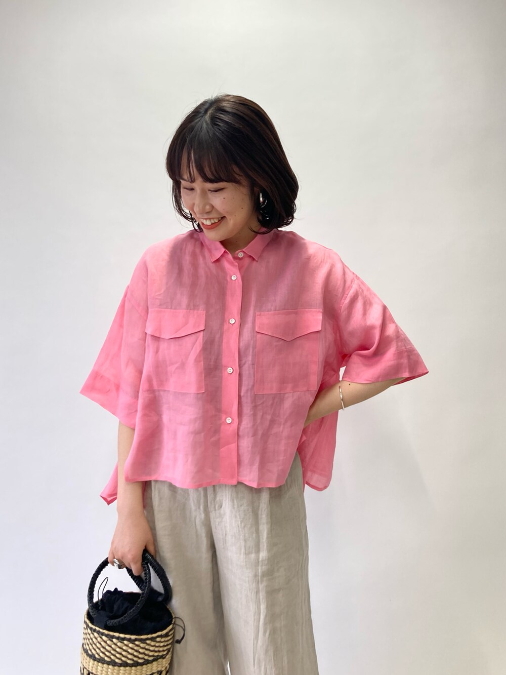 ピンク系のシャツ/ブラウス、ベージュ系のかごバッグ、ベージュ系のサンダルを着用したレディースの春コーディネートの3枚目の写真