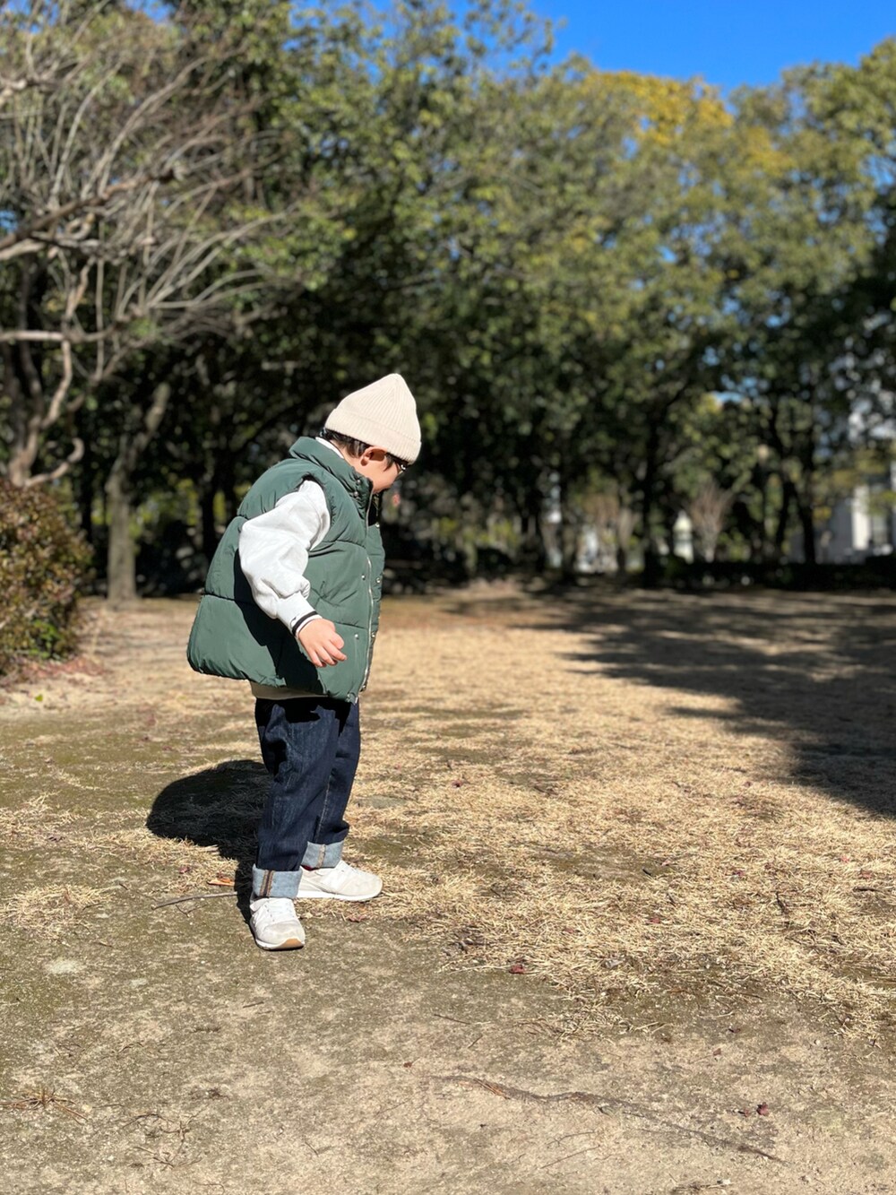 グレー系のスニーカー、グリーン系のダウンベスト、グレー系のスウェットを着用したキッズの冬コーディネートの2枚目の写真