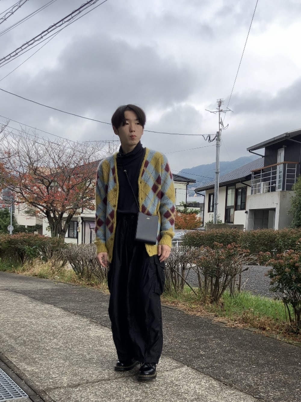 イエロー系のカーディガン/ボレロ、ブラック系のTシャツ/カットソー、ブラック系のパンツを着用したメンズの秋コーディネートの2枚目の写真