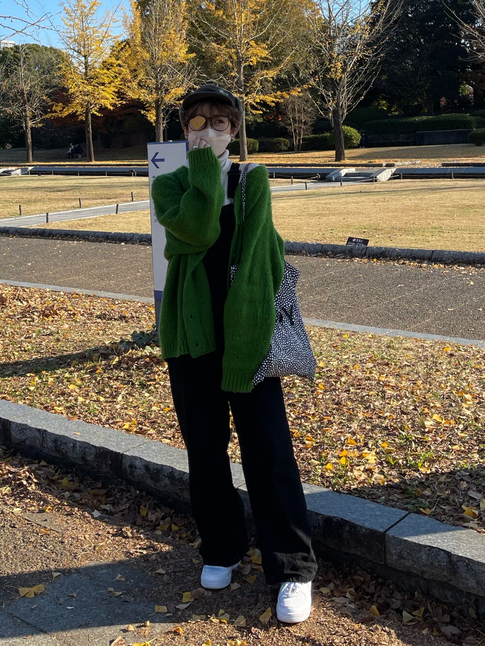 グリーン系のカーディガン/ボレロ、ブラック系のサロペット/オーバーオール、ホワイト系のスニーカーを着用したレディースの冬コーディネートの2枚目の写真