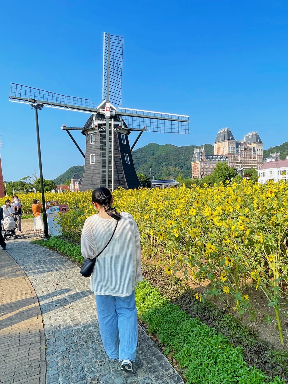 ブルー系のデニムパンツ、ブラック系のバッグ、ホワイト系のカーディガン/ボレロを着用したレディースの夏コーディネートの2枚目の写真