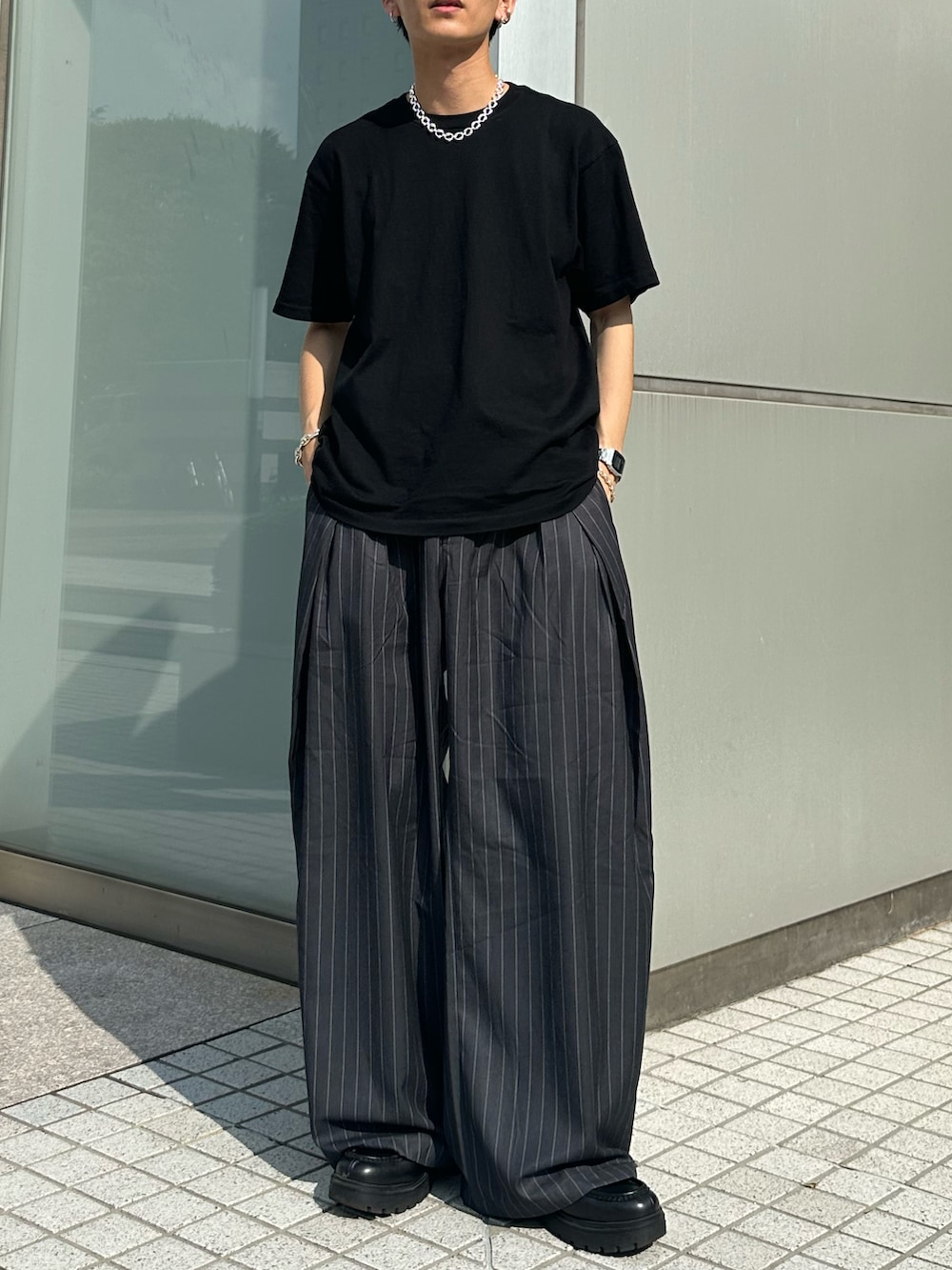 ブラック系のTシャツ/カットソー、グレー系のスラックス、シルバー系のネックレスを着用したメンズの夏コーディネートの3枚目の写真