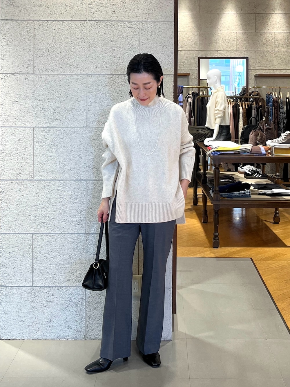 ホワイト系のニット/セーター、ブラック系のハンドバッグ、グレー系のその他パンツを着用したレディースの秋コーディネートの2枚目の写真