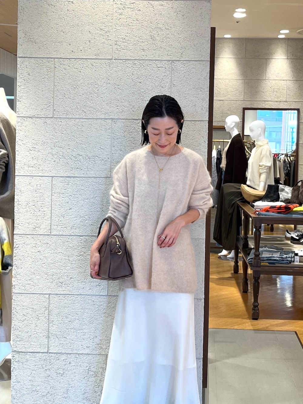 ホワイト系のスカート、ベージュ系のニット/セーター、ブラウン系のブーツを着用したレディースの秋コーディネートの2枚目の写真