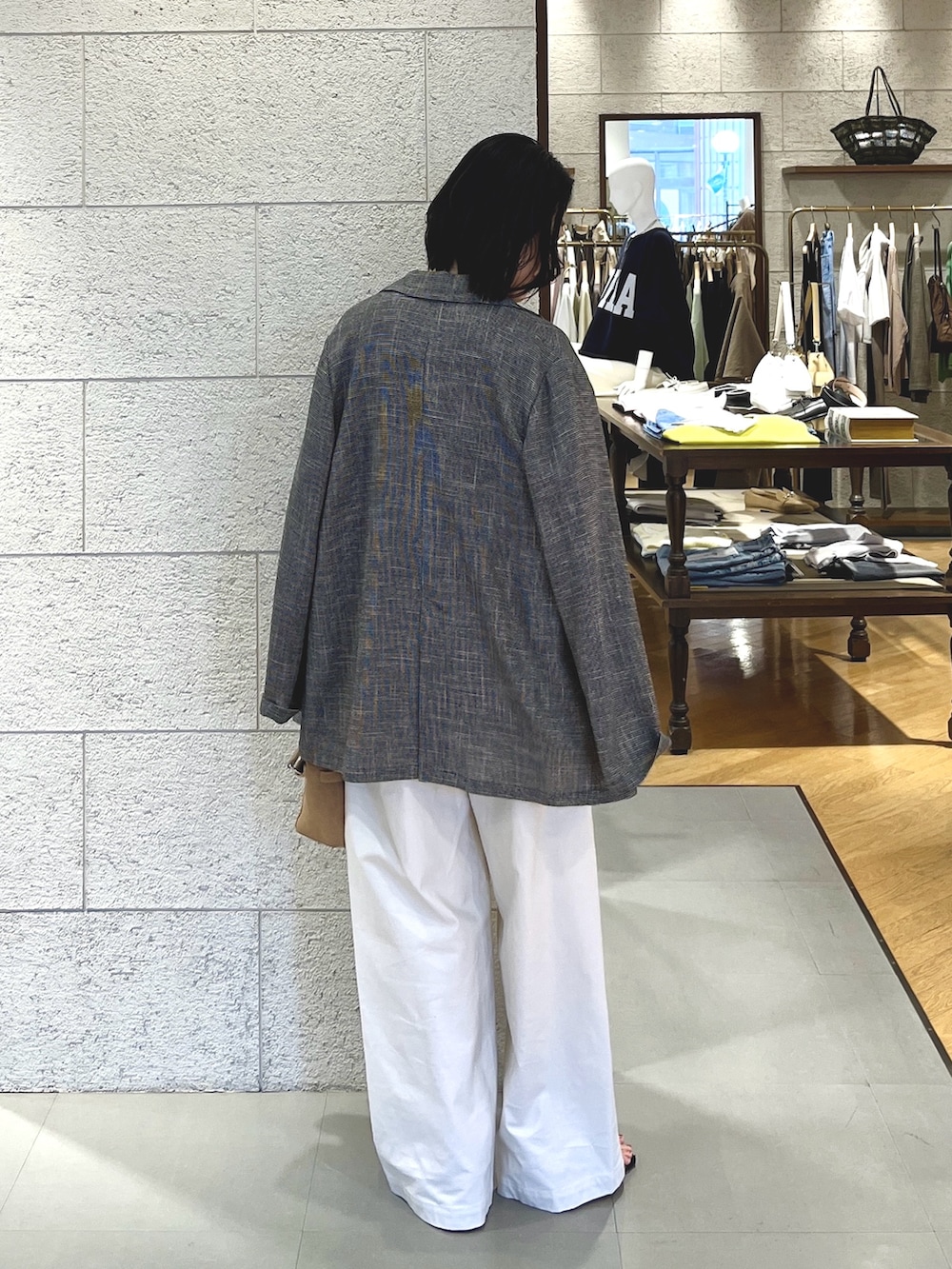 ブルー系のニット/セーター、ブラック系のテーラードジャケット、ホワイト系のチノパンツを着用したレディースの春コーディネートの4枚目の写真