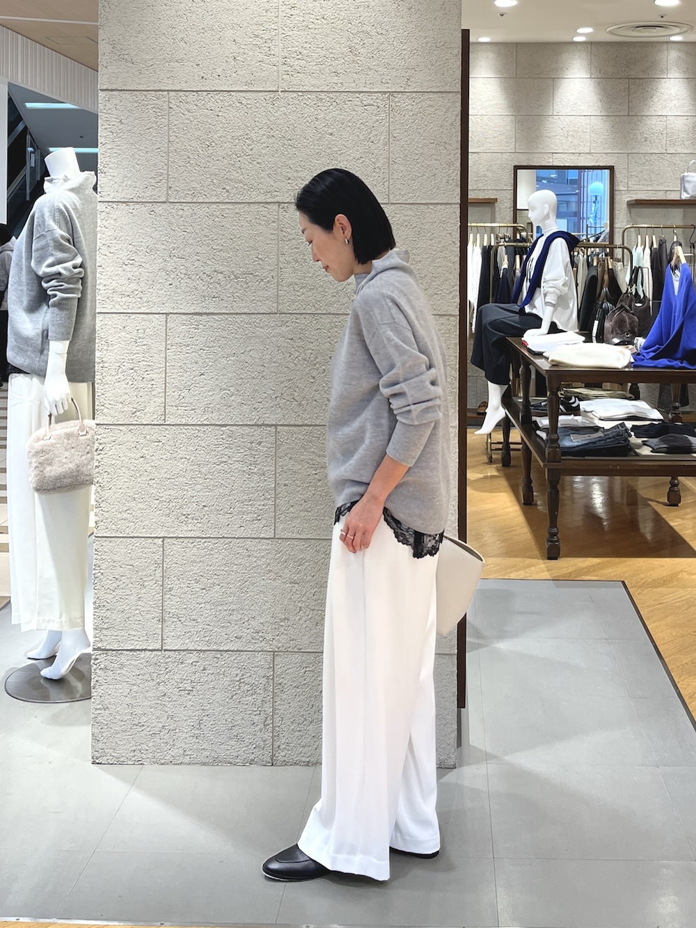 グレー系のニット/セーター、ブラック系のキャミソール、ホワイト系のスラックスを着用したレディースの冬コーディネートの3枚目の写真