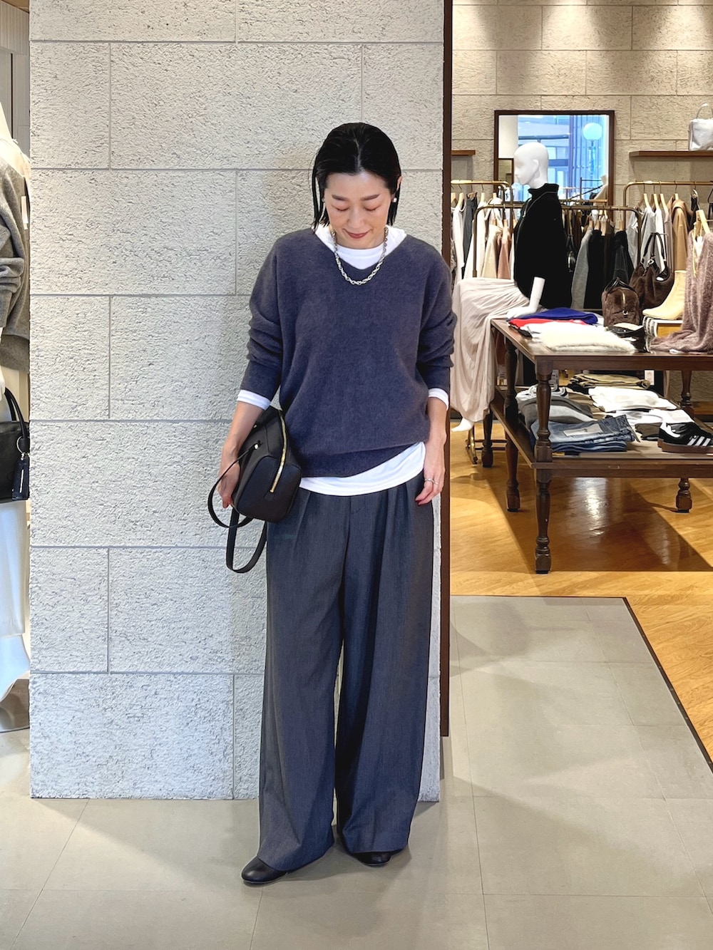 グレー系のニット/セーター、ホワイト系のTシャツ/カットソー、グレー系のスラックスを着用したレディースの冬コーディネートの2枚目の写真