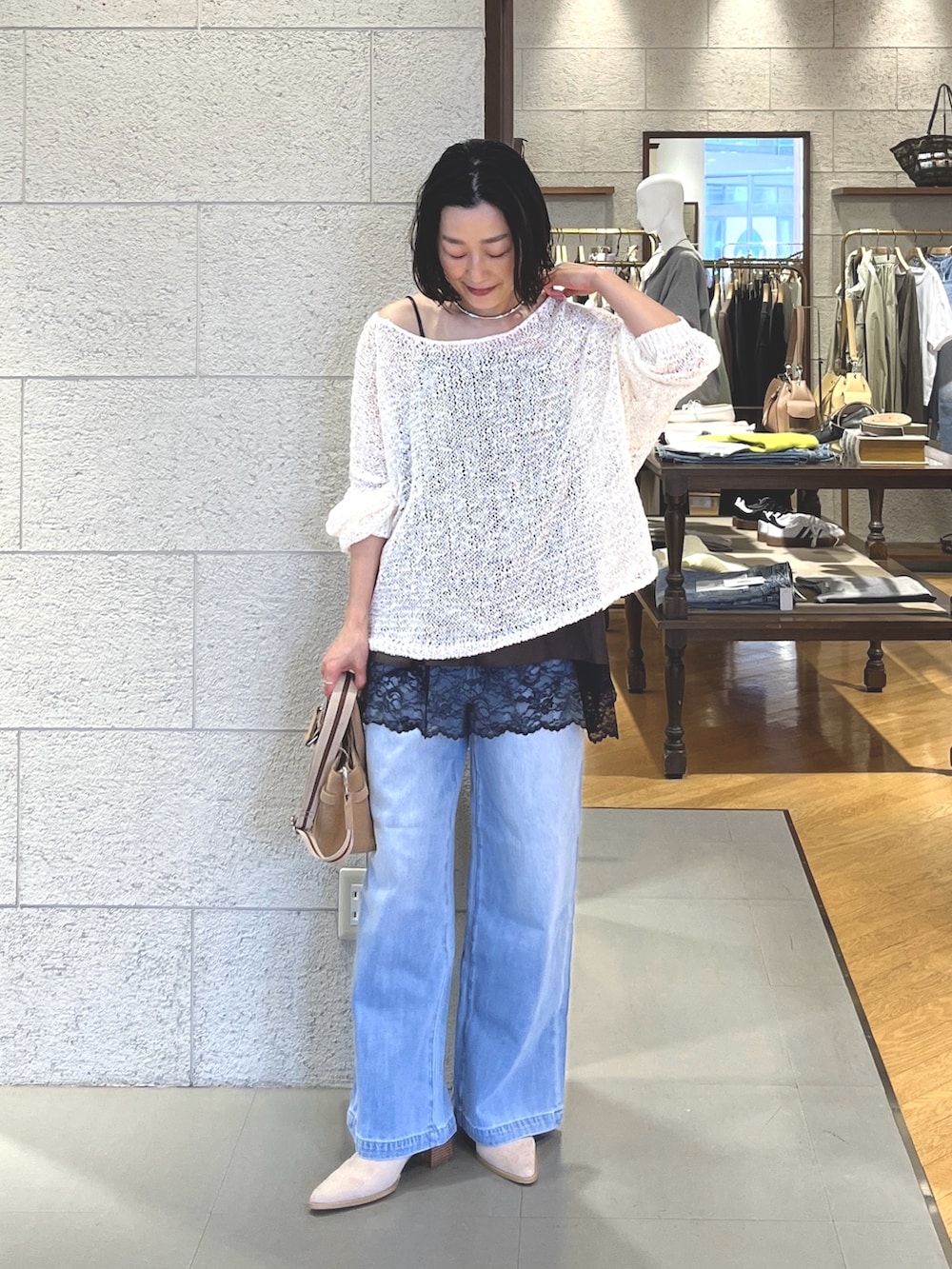 ホワイト系のニット/セーター、ブラウン系のキャミソール、ブルー系のデニムパンツを着用したレディースの春コーディネートの3枚目の写真