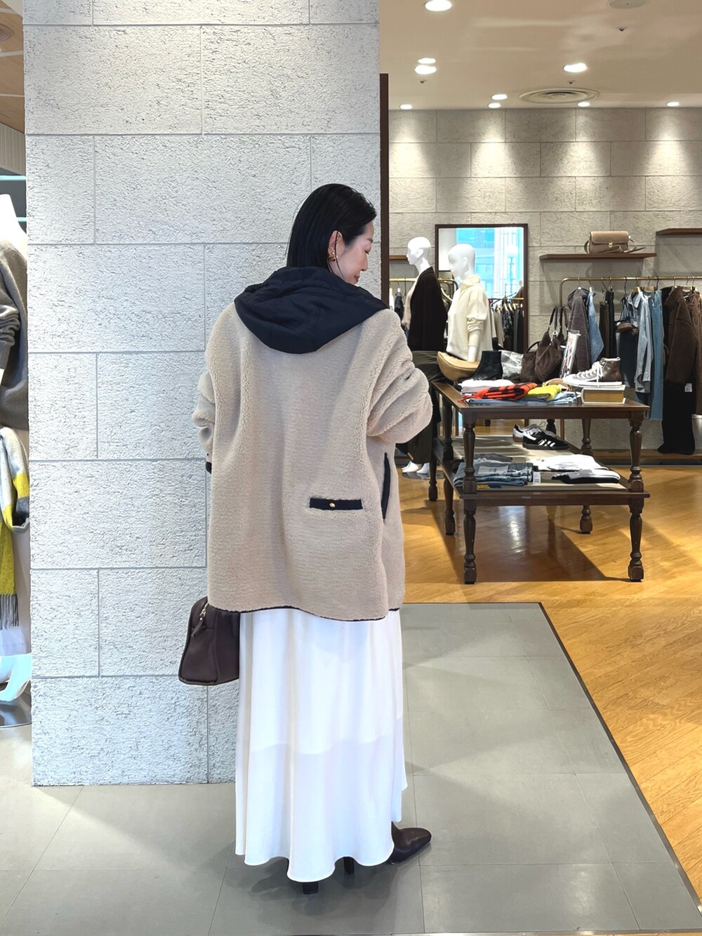 ホワイト系のスカート、ブラウン系のブーツ、ブラウン系のボストンバッグを着用したレディースの秋コーディネートの4枚目の写真