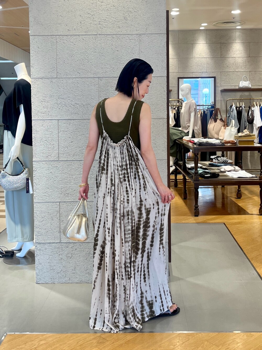 グリーン系のワンピース、ブルー系のデニムパンツ、グリーン系のニット/セーターを着用したレディースの夏コーディネートの3枚目の写真