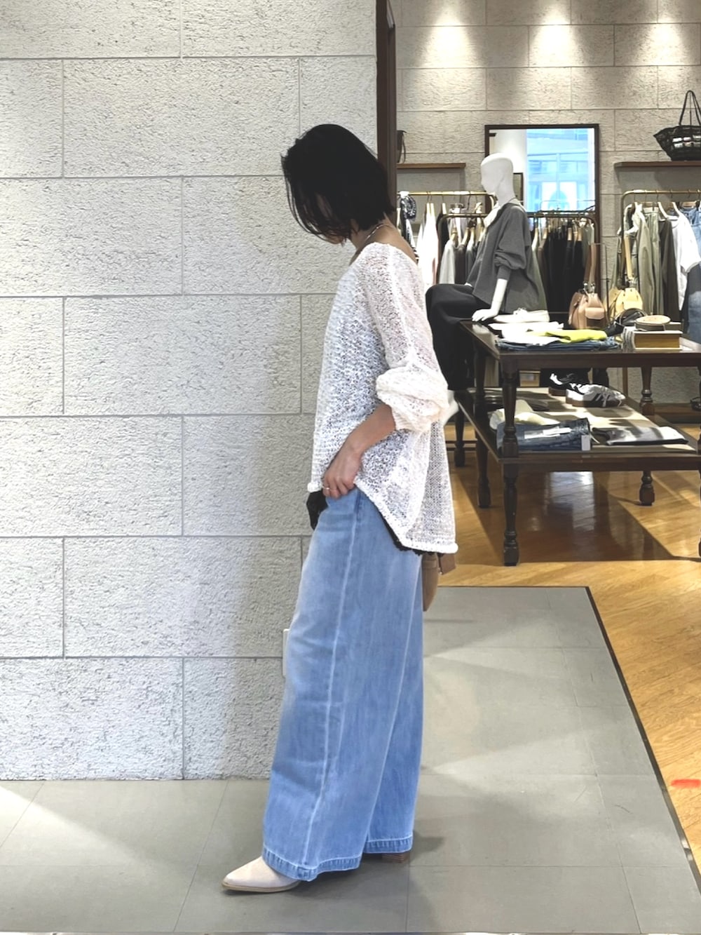 ホワイト系のニット/セーター、ブラウン系のキャミソール、ブルー系のデニムパンツを着用したレディースの春コーディネートの4枚目の写真