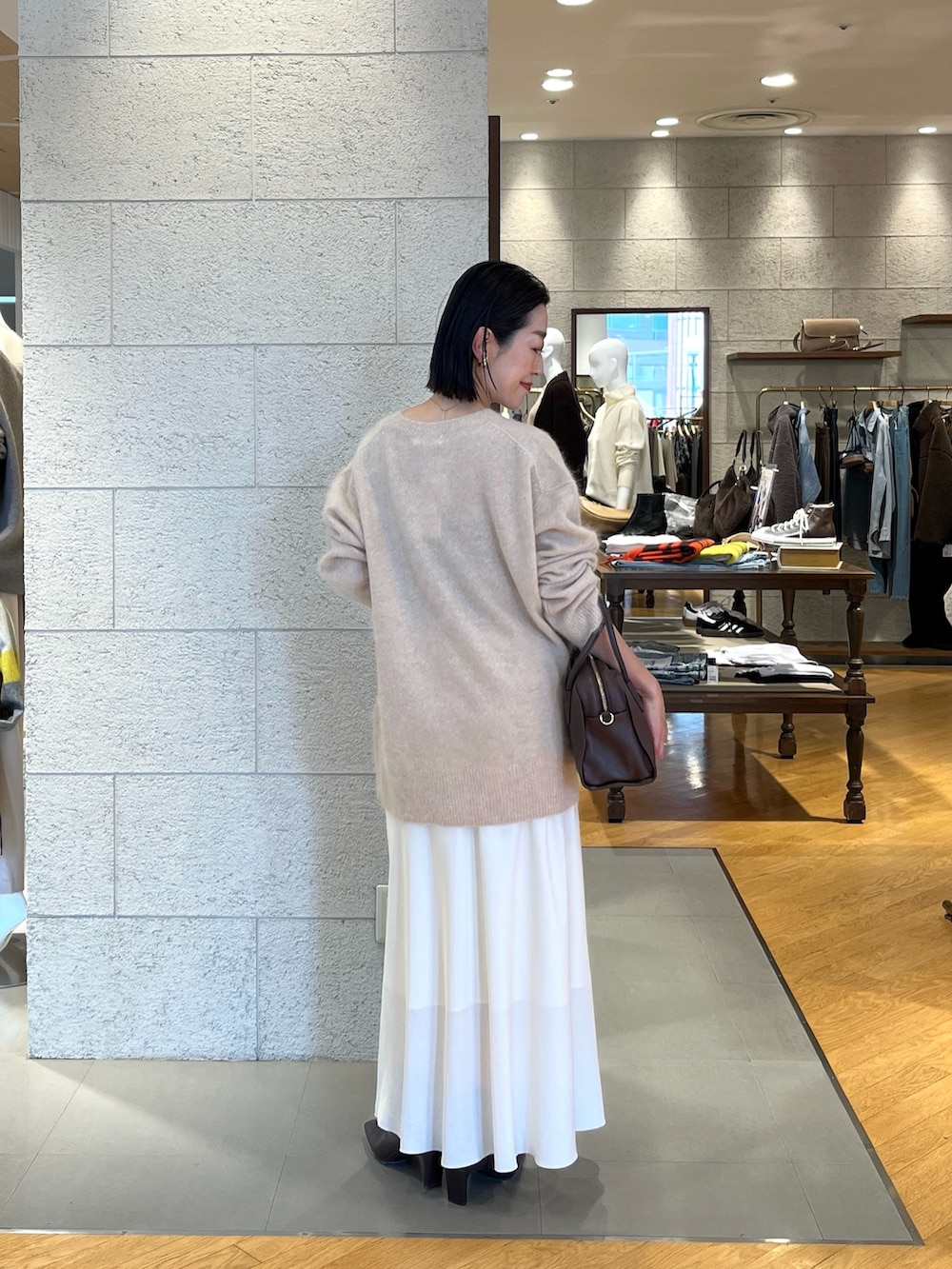 ホワイト系のスカート、ベージュ系のニット/セーター、ブラウン系のブーツを着用したレディースの秋コーディネートの4枚目の写真