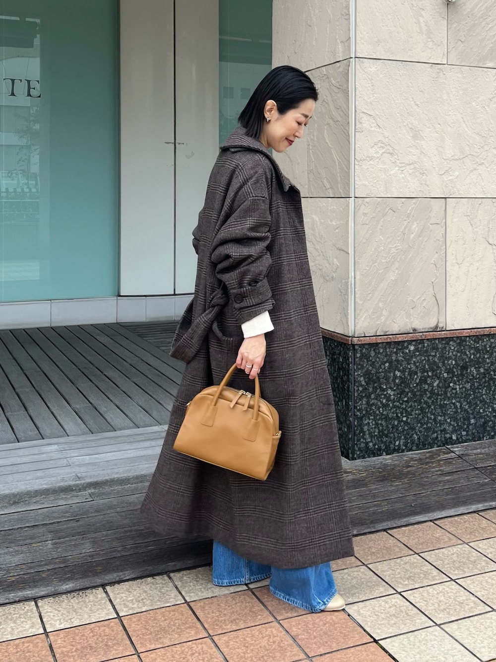 ブルー系のデニムパンツ、イエロー系のボストンバッグ、ベージュ系のブーツを着用したレディースの秋コーディネートの3枚目の写真