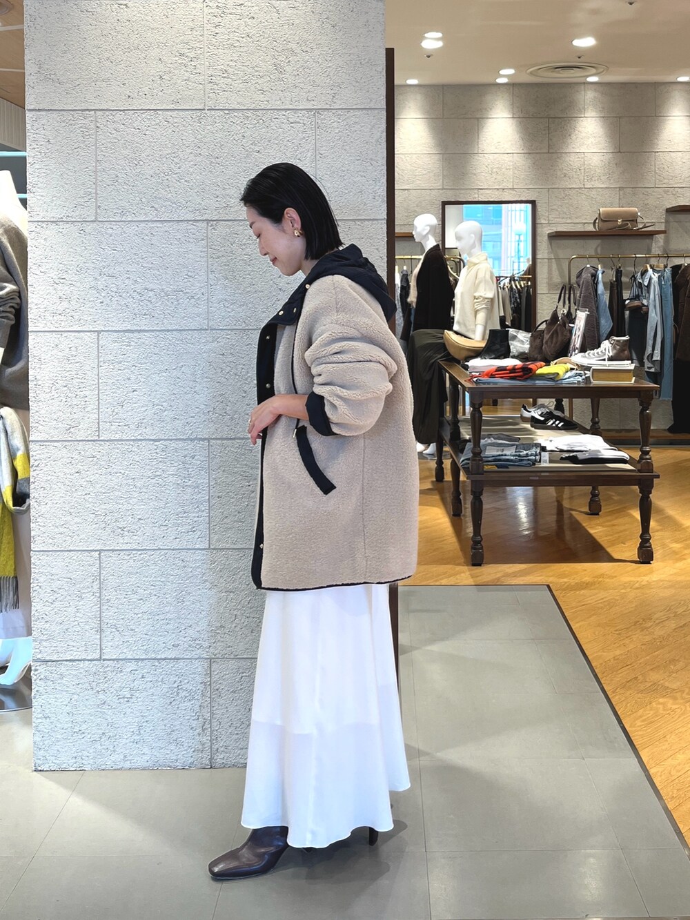 ホワイト系のスカート、ブラウン系のブーツ、ブラウン系のボストンバッグを着用したレディースの秋コーディネートの3枚目の写真