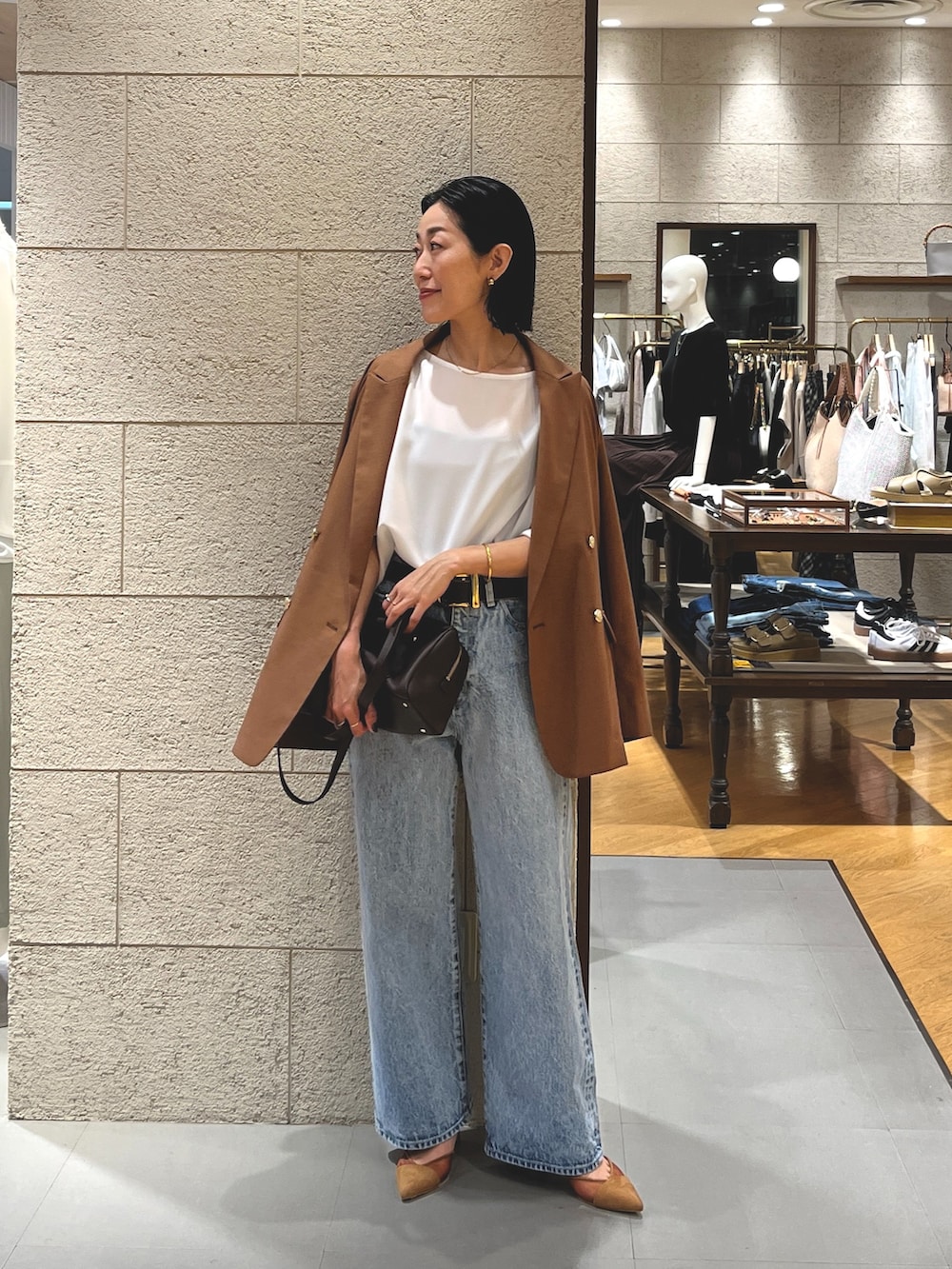 ブルー系のデニムパンツ、ブラウン系のパンプス、ブラウン系のショルダーバッグを着用したレディースの夏コーディネートの2枚目の写真