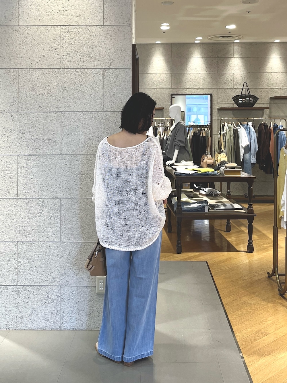 ホワイト系のニット/セーター、ブラウン系のキャミソール、ブルー系のデニムパンツを着用したレディースの春コーディネートの5枚目の写真