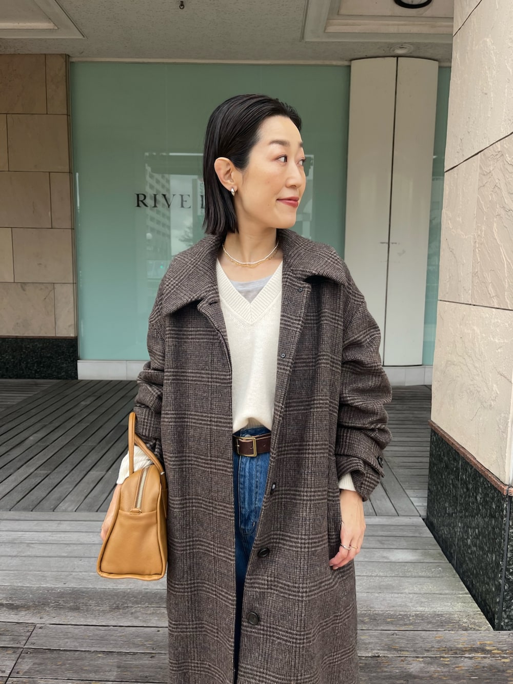 ブルー系のデニムパンツ、イエロー系のボストンバッグ、ベージュ系のブーツを着用したレディースの秋コーディネートの5枚目の写真