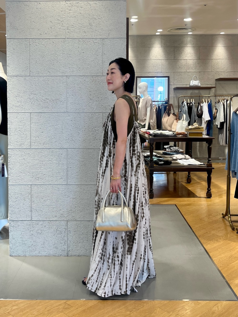 グリーン系のワンピース、ブルー系のデニムパンツ、グリーン系のニット/セーターを着用したレディースの夏コーディネートの2枚目の写真