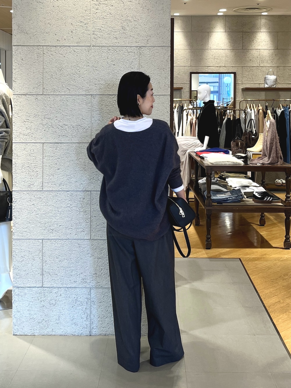 グレー系のニット/セーター、ホワイト系のTシャツ/カットソー、グレー系のスラックスを着用したレディースの冬コーディネートの4枚目の写真