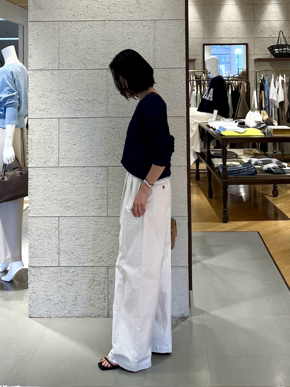 ホワイト系のチノパンツ、ベージュ系のトートバッグ、ブルー系のニット/セーターを着用したレディースの春コーディネートの3枚目の写真