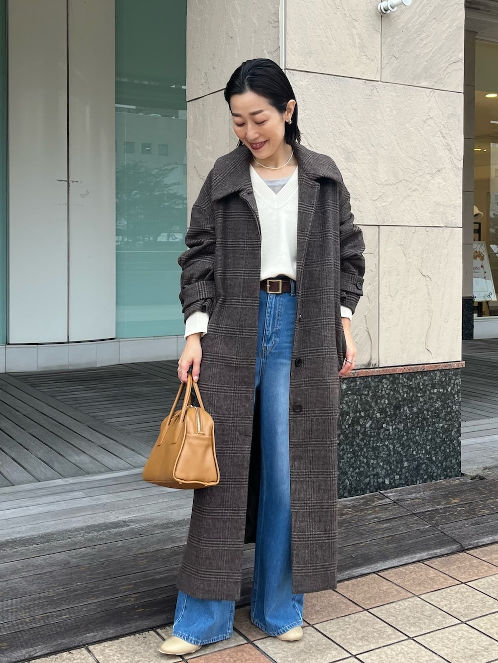 ブルー系のデニムパンツ、イエロー系のボストンバッグ、ベージュ系のブーツを着用したレディースの秋コーディネートの2枚目の写真