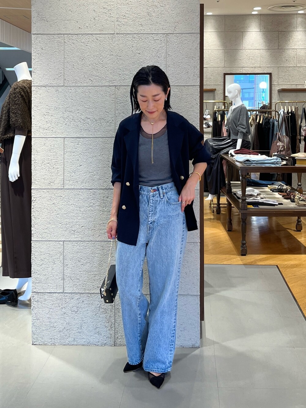 ブラック系のパンプス、ブルー系のテーラードジャケット、ブルー系のデニムパンツを着用したレディースの夏コーディネートの2枚目の写真