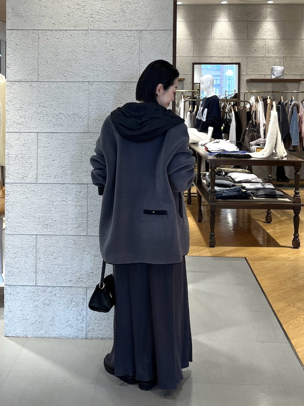 グレー系のスカート、ブラック系のブーツ、ブラック系のハンドバッグを着用したレディースの冬コーディネートの4枚目の写真