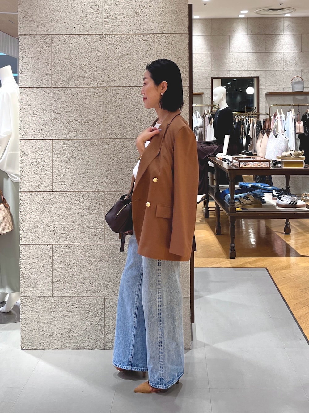 ブルー系のデニムパンツ、ブラウン系のパンプス、ブラウン系のショルダーバッグを着用したレディースの夏コーディネートの3枚目の写真