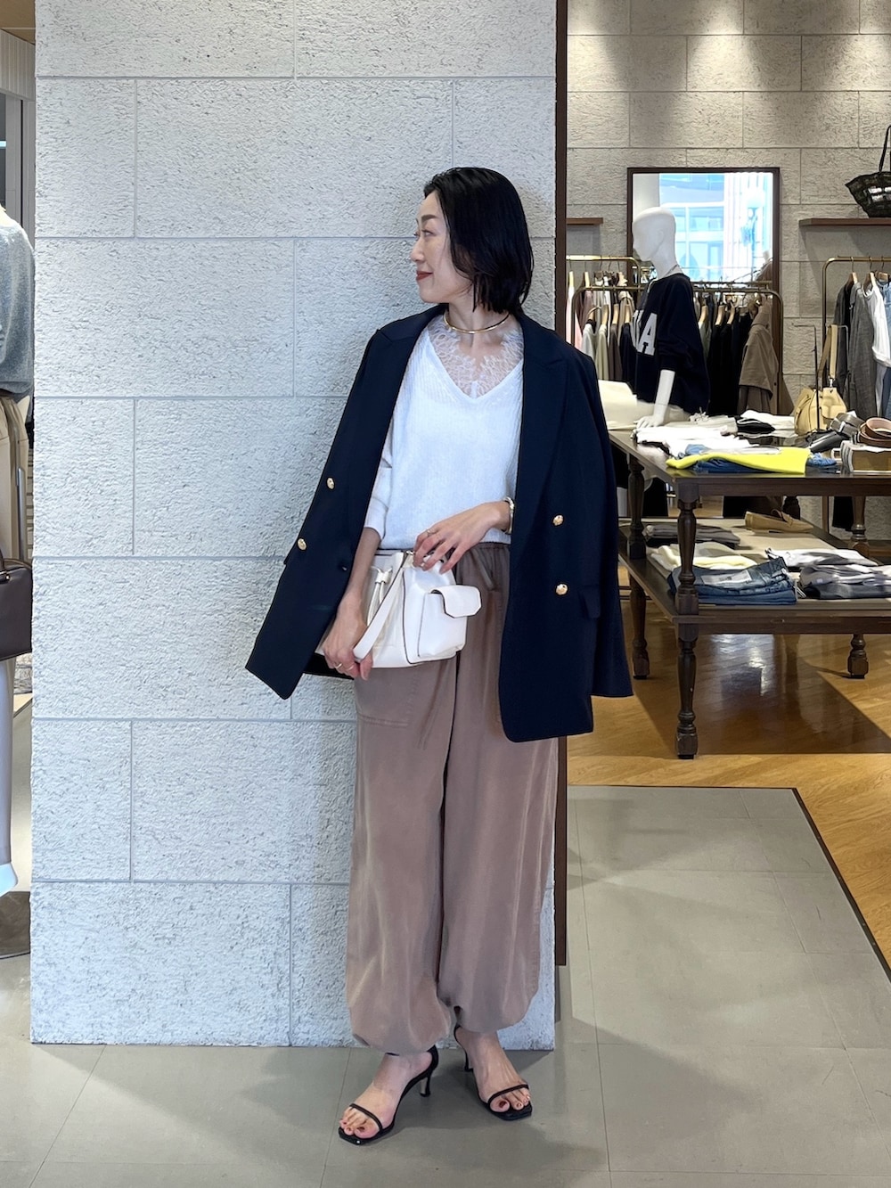 ホワイト系のショルダーバッグ、ホワイト系のニット/セーター、ブラウン系のその他パンツを着用したレディースの春コーディネートの3枚目の写真