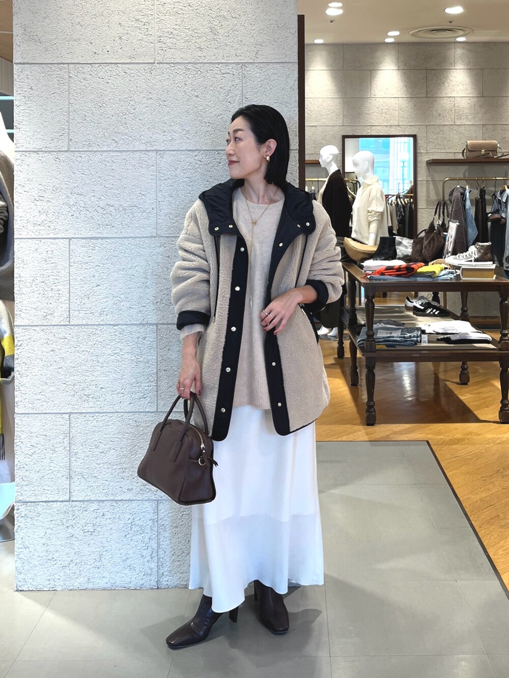 ホワイト系のスカート、ブラウン系のブーツ、ブラウン系のボストンバッグを着用したレディースの秋コーディネートの2枚目の写真