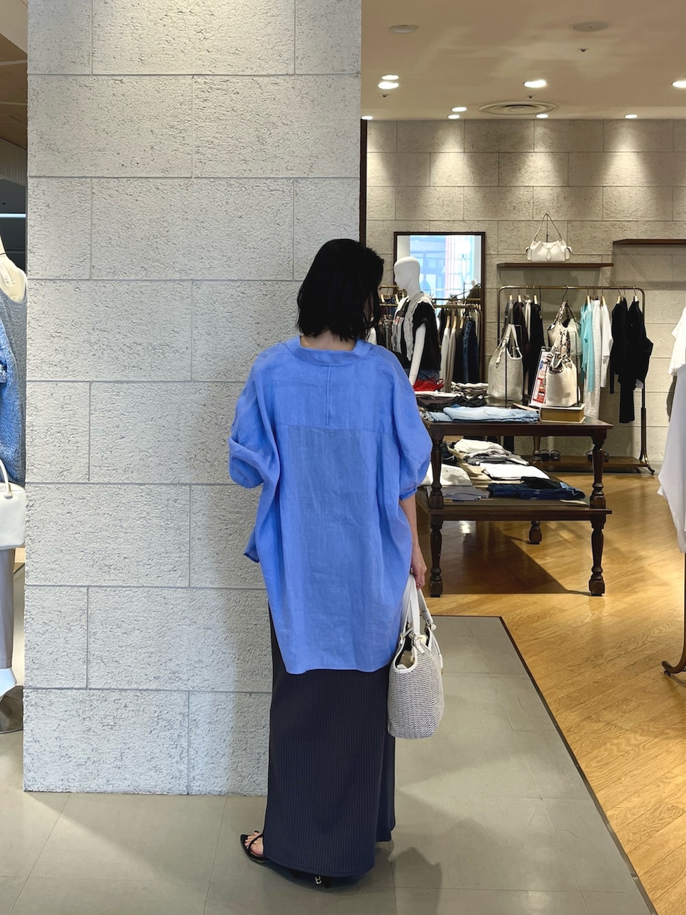 グレー系のワンピース、ブラック系のサンダル、ホワイト系のハンドバッグを着用したレディースの春コーディネートの4枚目の写真