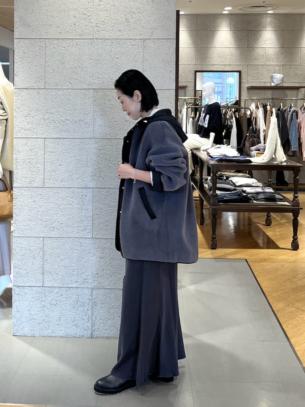 グレー系のスカート、ブラック系のブーツ、ブラック系のハンドバッグを着用したレディースの冬コーディネートの3枚目の写真