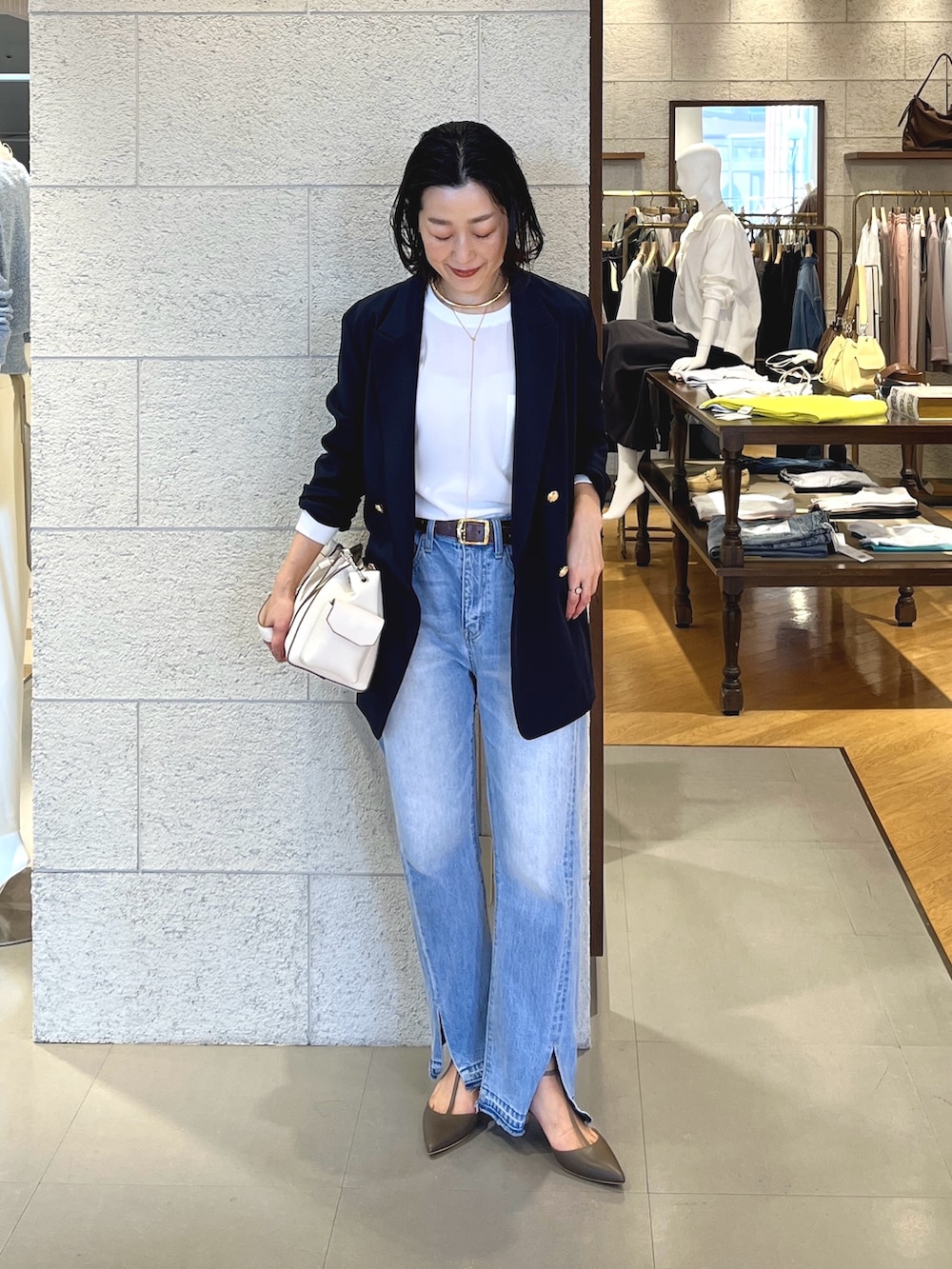 ブルー系のデニムパンツ、グレー系のその他シューズ、ホワイト系のショルダーバッグを着用したレディースの春コーディネートの2枚目の写真